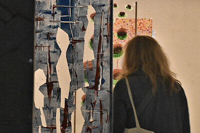 Blick auf einen Teil des Kunstprojektes von Schüler*innen des Gymnasiums Dörpsweg  mit farbigen Tafeln und eine Person, die sich die Tafeln anschaut